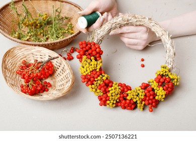 Penjual bunga sedang bekerja: seorang wanita menunjukkan cara membuat karangan bunga musim gugur dengan buah rowan dan tansy. Tutorial langkah demi langkah.