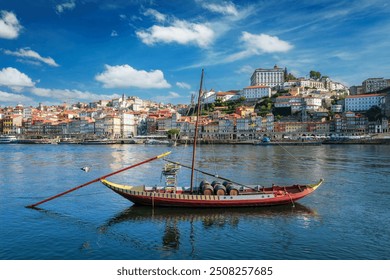 View of Porto city and Douro river with traditional boat with port wine barrels from famous tourist viewpoint Marginal de Gaia riverfront. Porto, Vila Nova de Gaia, Portugal