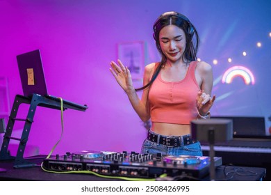 Una joven artista asiática DJ mezclando y haciendo scratch con el controlador de la mesa de mezclas. Una atractiva DJ se divierte mezclando música en la consola tocando botones y tocando música electrónica en una fiesta de neón.