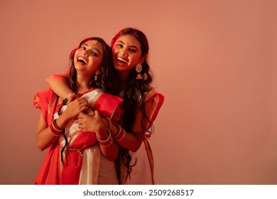Deux sœurs bengali en sari blanc s'embrassant sur fond uni