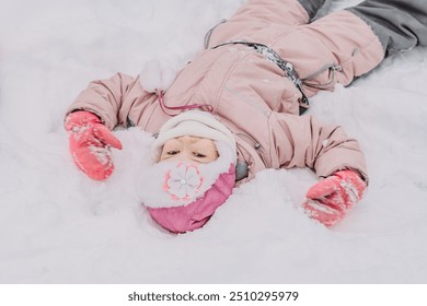 A little girl is playing in the snow outside in the park, snowball games, sculpting a castle out of snow, games in the snow, climate change, happy moments outdoors. Winter Vacation.
