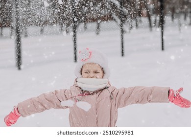 A little girl is playing in the snow outside in the park, snowball games, sculpting a castle out of snow, games in the snow, climate change, happy moments outdoors. Winter Vacation.