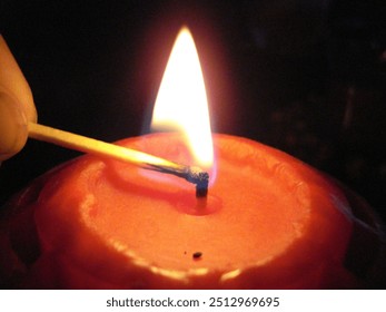 Menyalakan lilin merah dengan mancis.