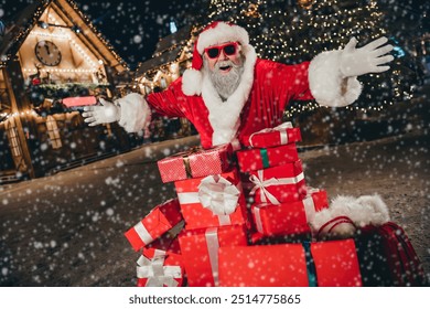Fotografija presretnog funky ludog djeda koji kupuje mnogo darova koji vam predstavlja otvorene ruke sretna nova godina adventski duh na otvorenom