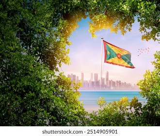 Grenada-Flagge weht mit moderner Skyline. Eine Flagge weht hinter den Baumblättern. Grenada-Nationalflagge zum Unabhängigkeitstag.