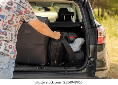 En verano, un hombre se va de vacaciones en coche. Carga el equipaje en el maletero de su coche (de la serie "El equipaje").