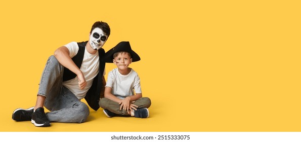 Papp a säi klenge Jong verkleed fir Halloween als Piraten déi op gielem Hannergrond sëtzen mat Plaz fir Text