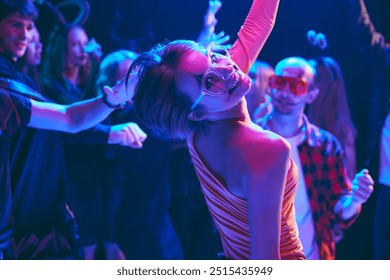 Groupe de jeunes amis en costumes d'Halloween qui rient ensemble lors d'une fête en boîte de nuit, dansent joyeusement et s'amusent. Concept d'Halloween, vacances, fête, loisirs