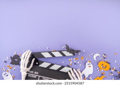 Horror movie, series night, Halloween cinema party with trick-or-treating sweets bucket, popcorn, movie clapperboard and Halloween decorations on high-colored background copy space