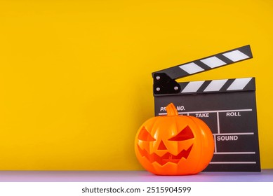 Horror movie, series night, Halloween cinema party with trick-or-treating sweets bucket, popcorn, movie clapperboard and Halloween decorations on high-colored background copy space