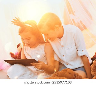 Children, tablet and outdoor for streaming movies, playing dress up and online games for fantasy. Siblings, kids and sun flare for entertainment in fort or tent, brother and sister for watching film