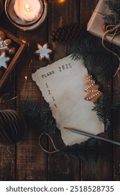 12月の大晦日に2025年の新年の抱負を手書きで書きます。計画、目標、アイデア、プロジェクト。居心地の良い家庭の休日の雰囲気、クリスマスのイルミネーション、お祭りの装飾、手作りのジンジャーブレッドクッキー