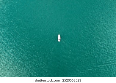 A serene aerial view of a lone boat on calm turquoise waters, capturing the tranquility of nature and leisure activities. Ideal for travel and lifestyle themes.