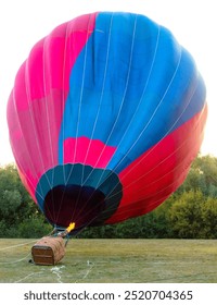 Un globo aerostático está en el aire con fuego en su interior. El globo es rojo y azul.
