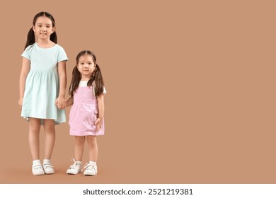 น้องสาวชาวเอเชียตัวน้อยน่ารักมีความสุขบนพื้นหลังสีเบจ