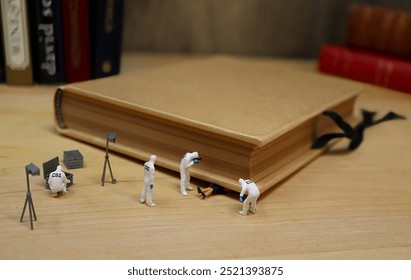 Miniaturní tým CSI vyšetřuje ženu rozdrcenou knihou z knihovny.