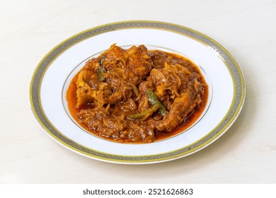 Homemade, delicious Rui fish curry (or Rui mach bhuna) served in a white plate on a light wooden table. Traditional Bengali cuisine.
