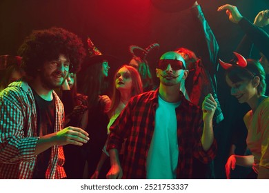 若者のグループ、ナイトクラブでのハロウィーン パーティーのテーマに合わせた衣装を着た友人、ダンス、不気味な休日のお祝い、そして楽しい時間。ハロウィーン、休日、パーティー、レジャーのコンセプト