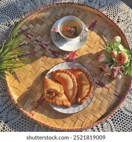 Kue Pastel, një rostiçeri tradicionale indoneziane, tortë paste mishi e mbushur me pulë dhe karrota. Me çaj Goji Berry të shërbyer në një tabaka bastun prej palme kacavjerrëse sipër mbulesës me grep