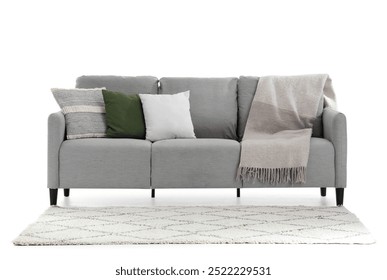 Graues Sofa mit Kissen, Plaid und Teppich auf weißem Hintergrund