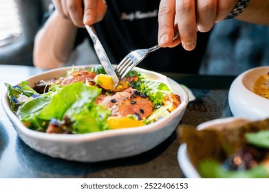 persona che gusta un'insalata colorata con verdure fresche e carne, usando forchetta e coltello. L'attenzione è rivolta al pasto sano e vivace, evidenziando il tema di un'alimentazione nutriente e di uno stile di vita equilibrato.