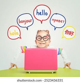 Foreign language learning concept of a beautiful cute little girl with eyeglasses behind a laptop on table. Hello word in Spanish, French, Russian and Chinese.