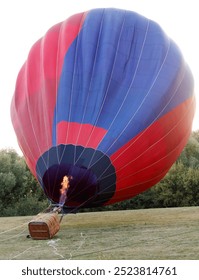 Un globo aerostático está en el aire con fuego en su interior. El globo es rojo y azul.