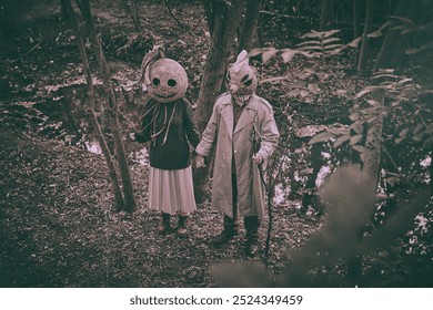 Persone inquietanti e terrificanti in piedi nel profondo di una foresta, con maschere inquietanti e abiti strani, che si tengono per mano. Fotografia in stile vintage. Concetto di Halloween, stagione spettrale, stile retrò.