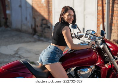 Wanita berambut coklat mengenakan celana pendek di atas sepeda motor merah.