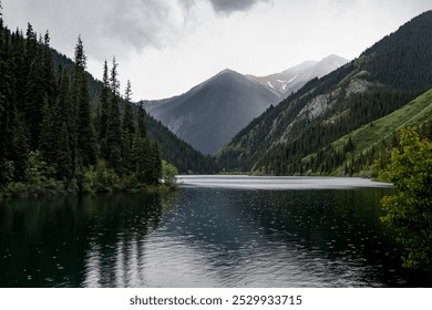 Kolsai high-altitude lake in the Tien Shan mountain system, Kazakhstan. Summer day, rainy weather. Travel, tourism, vacation, outdoor recreation.