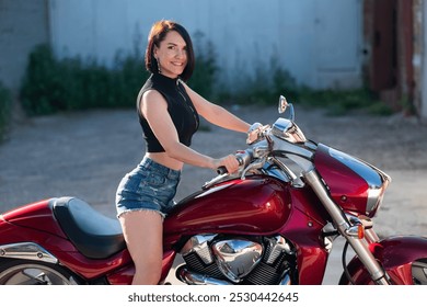 Brunetka v šortkách na červenej motorke.