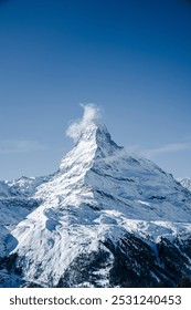 澄み切った青空の下、雄大な雪に覆われた山頂。頂上には小さな雲が浮かんでいます。素晴らしいアルプスの風景です。