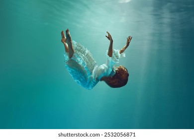 Tomber dans l'inconnu. Scène créative sous-marine surréaliste mettant en scène une élégante jeune femme lévitant gracieusement sous l'eau. Concept de surréalisme, de beauté, de mystère et de fantaisie, de liberté