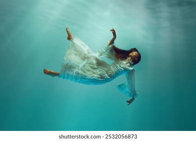 Trouver la paix intérieure. Moment serein sous l'eau avec une jeune fille élégante dans une robe blanche tendre lévitant avec une expression calme sous l'eau. Concept de surréalisme, de beauté, de mystère et de fantaisie, de liberté