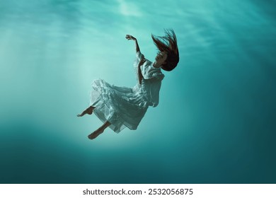 Image féerique montrant une scène mystérieuse sous-marine avec une jeune fille élégante en robe tendre lévitant dans l'océan. Concept de surréalisme, de beauté, de mystère et de fantaisie, de liberté