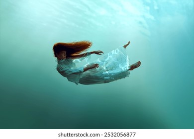 Image créative représentant une jeune fille rousse calme en lévitation sous l'eau mettant en valeur l'harmonie entre l'homme et la nature. Concept de surréalisme, de beauté, de mystère et de fantaisie, de liberté