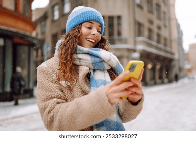 Telefone na mão de uma jovem em uma rua de inverno. Comunicação online. Conceito de tecnologia.