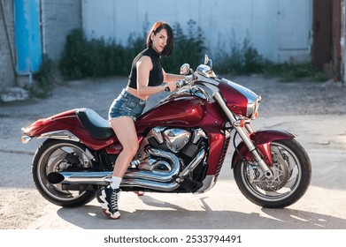 Brunetka v šortkách na červenej motorke.