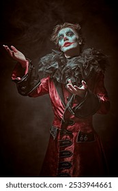 Drama, tragedy. Performance in the theater. A dramatic young man - an actor with clown, joker makeup looking to the camera with horror and suffering in his eyes. Black background.
