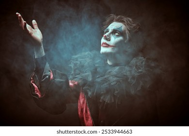 Drama, tragedy. Old Circus concept. A young man - a dramatic and comic actor with a clown, joker makeup - looks at the camera sadly. Retro sepia portrait. Halloween.
