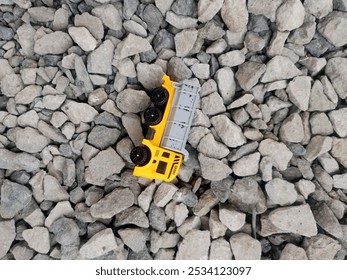 un camion giocattolo giallo per bambini adagiato sul cortile roccioso