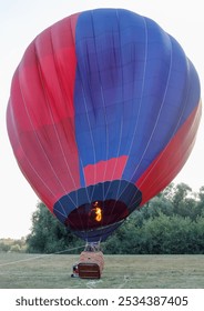 Un globo aerostático está en el aire con fuego en su interior. El globo es rojo y azul.