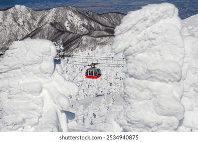 Teleféricos que sobrevuelan los bosques de Juhyo (árboles de hielo o monstruos de nieve) por toda la ladera de la estación de esquí y aguas termales de Zao, con montañas bajo un cielo azul claro en un soleado día de invierno, en Yamagata, Japón