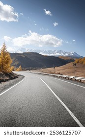highland road. autumn highway in front of ice peaks.