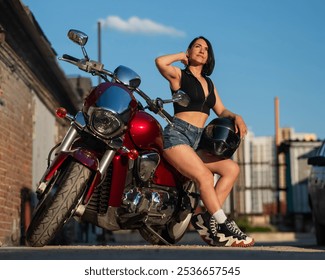 Brunetka v šortkách pózuje na červenej motorke.