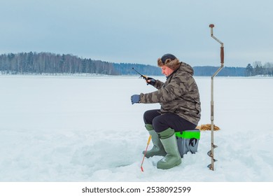 Un homme seul pêche dans un trou de glace sur un lac en hiver. Pêche d'hiver, pêche sur glace. Hobby, concept de temps libre en hiver.