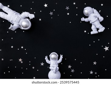 Figurka astronauta sedící na Měsíci obklopená dalšími kosmonauty a hvězdnými konfetami. Selektivní fokus, prostor pro kopírování.