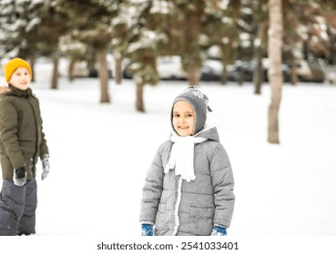 Happy teen boy and girl playing with snowball outdoor in nature. Children winter activity.