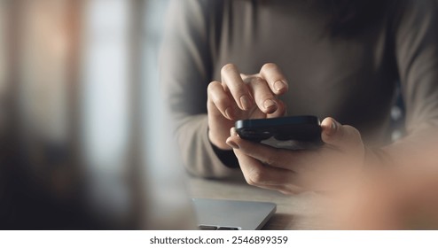 Close up, business woman using mobile phone with laptop computer on office table. Woman using smartphone for online shopping and digital banking via mobile app, social media marketing