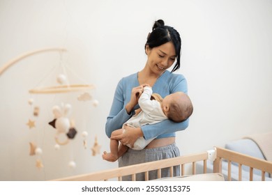 Loving Asian mom holding baby at home